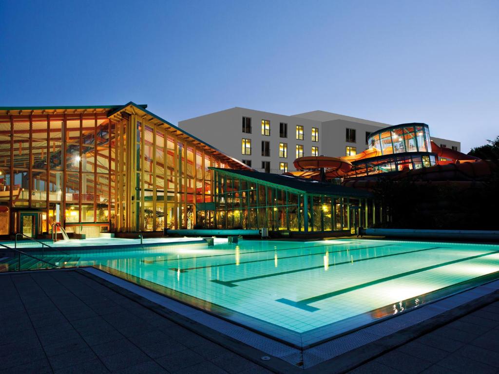 维斯马WONNEMAR Resort-Hotel的一座大型建筑,晚上设有游泳池