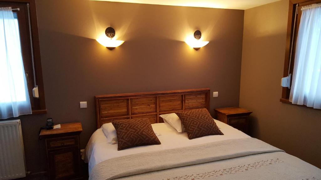 勒梅尼勒莱斯萨潘斯酒店的卧室配有一张床,墙上有两盏灯