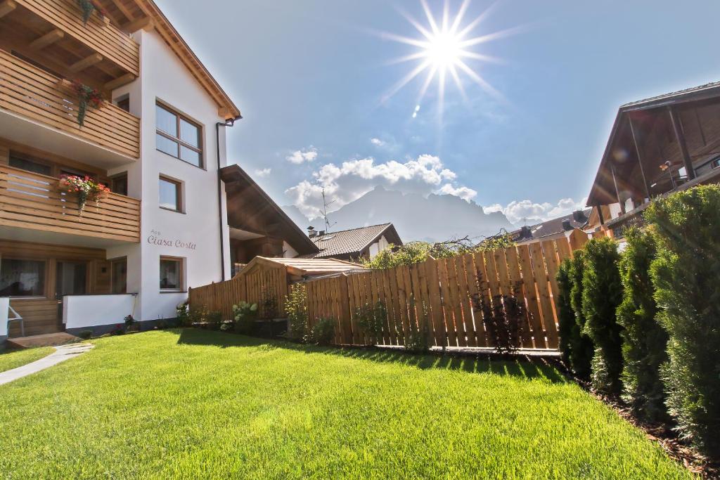 巴迪亚Apartments Ciasa Costa的后院设有木栅栏和绿色草地