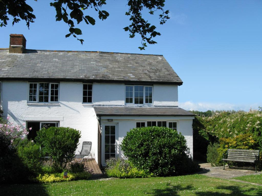 淡水Tollgate Cottages Bed and Breakfast的院子里有长凳的白色房子