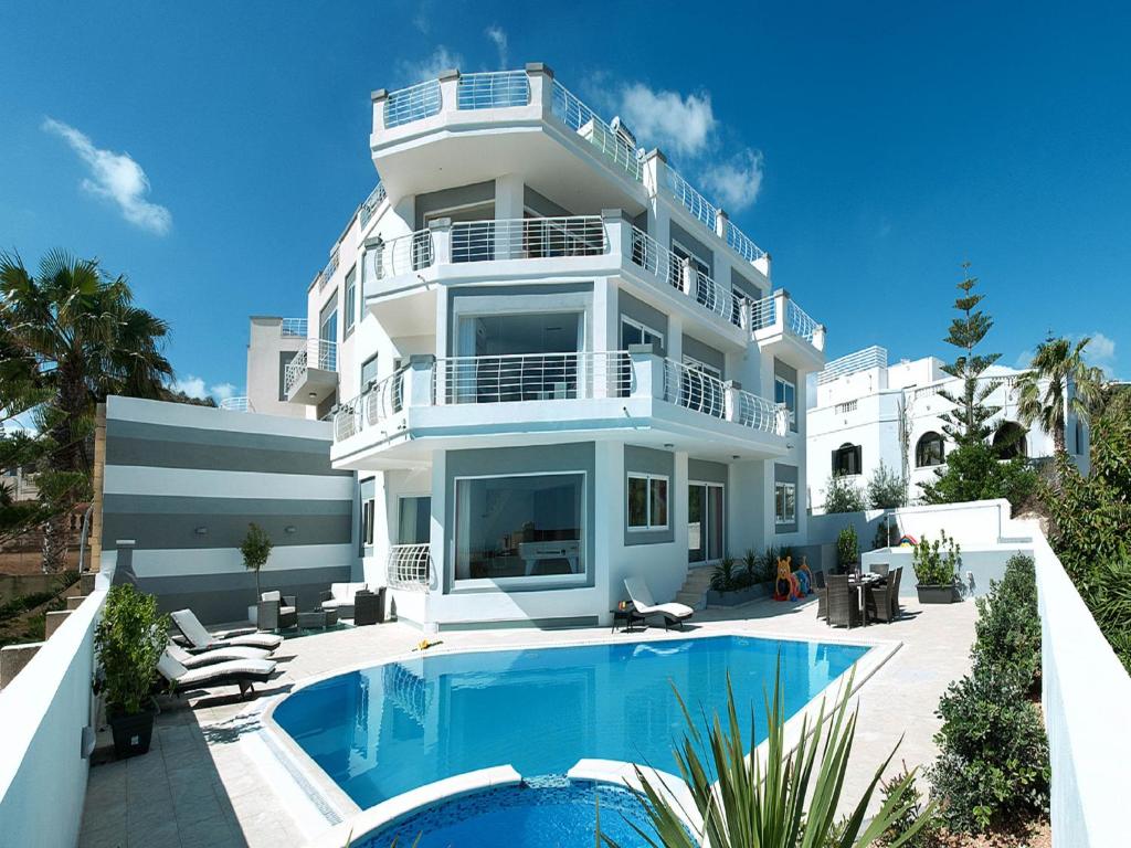 圣朱利安斯Villa belvedere的一座白色的大建筑,前面设有一个游泳池