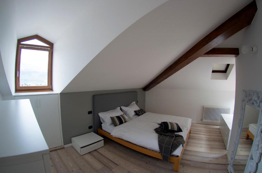 加尔达湖滨Appartamento i Sentieri 23的阁楼上的卧室设有一张床,设有窗户