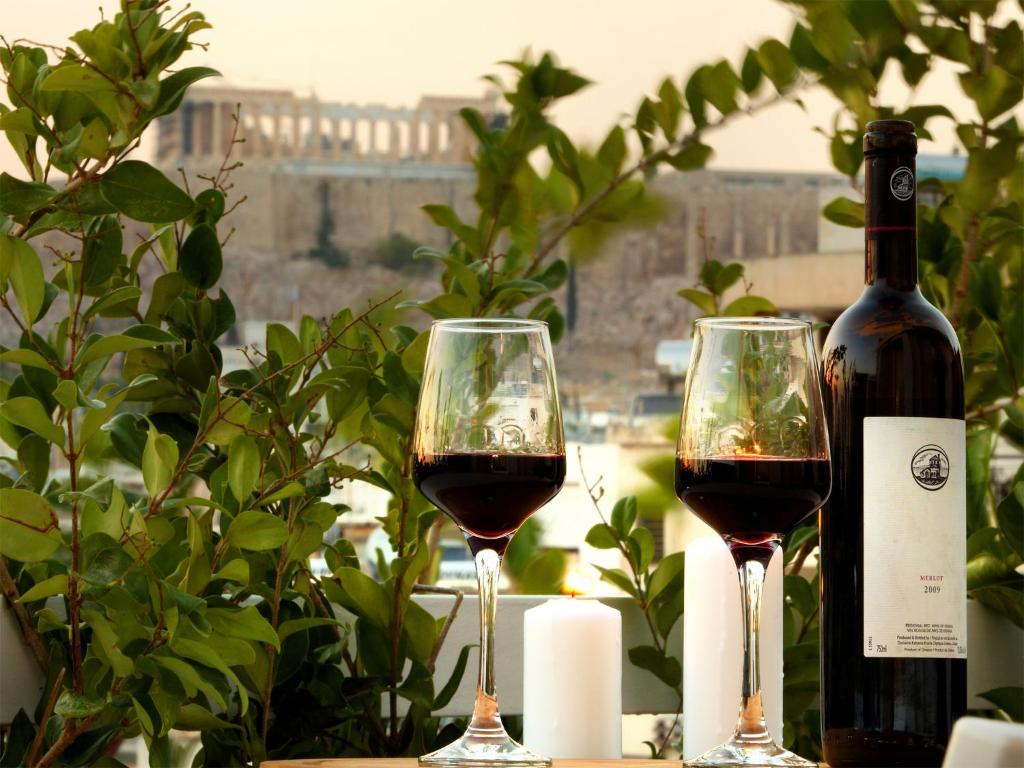 雅典雅典景致阁楼 - 01公寓的两杯红葡萄酒,旁边是一瓶葡萄酒