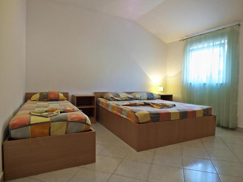 罗戈兹尼察拉迪克公寓的一间卧室设有两张床和一个带窗帘的窗户。