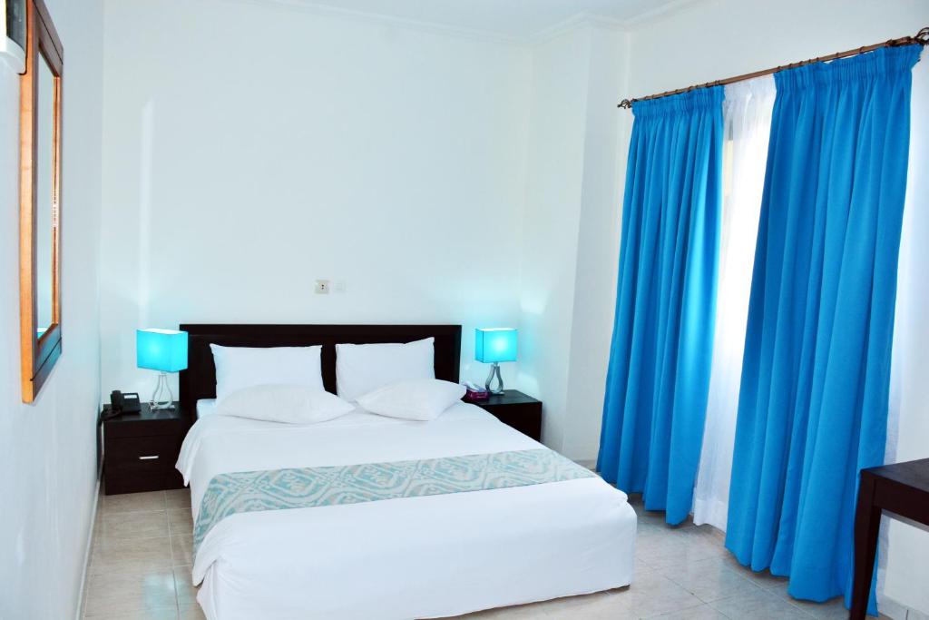 阿比让Hotel Djigui的一间卧室配有一张带蓝色窗帘的大床
