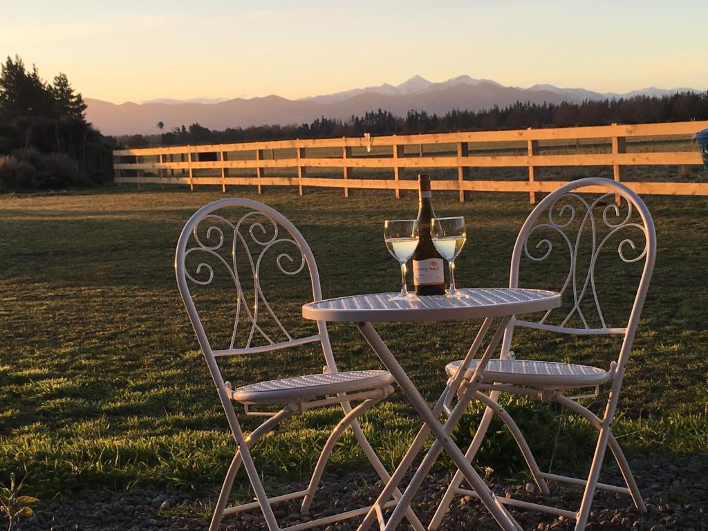 HawardenBentleys Country Stay的一张桌子、一瓶葡萄酒和两把椅子