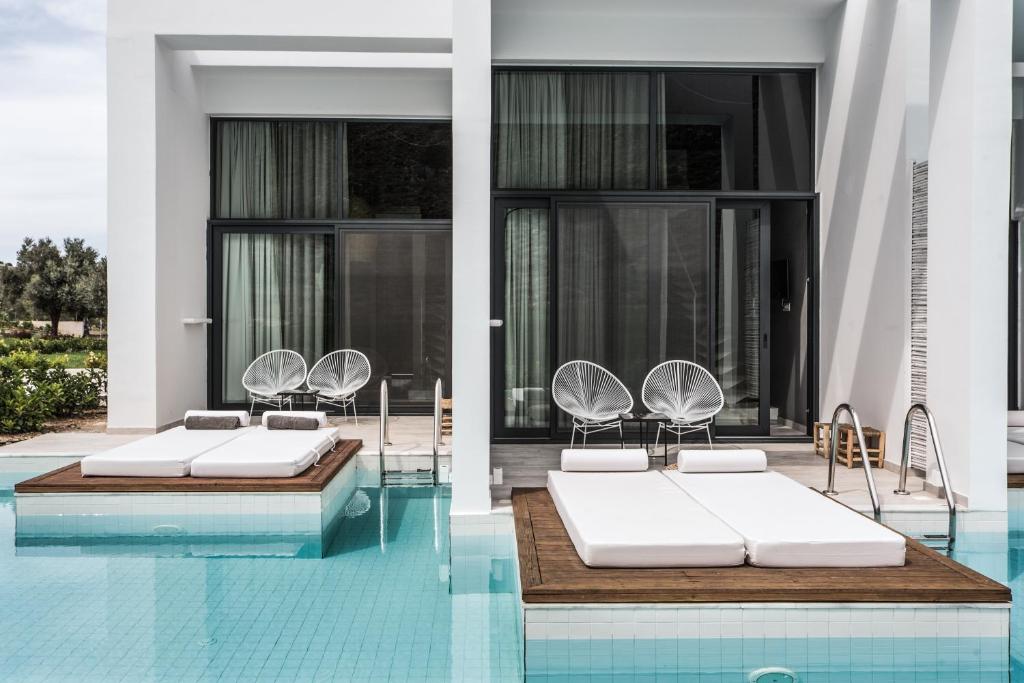 科林比亚罗德库克酒店（仅限成人）的大楼内一个带两张床和椅子的游泳池