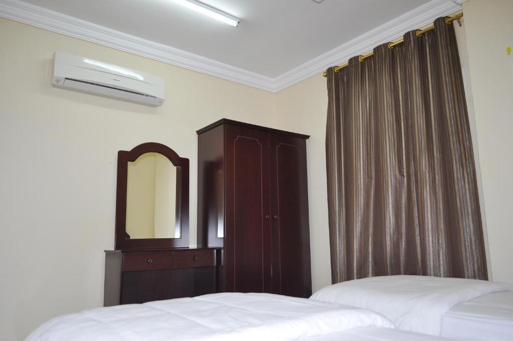 塞拉莱Ganaen Salalah的一间卧室配有两张床、一个梳妆台和镜子