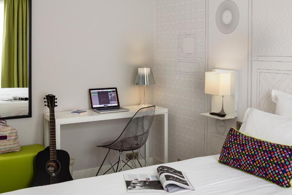 巴黎巴黎伏吉拉尔酒店的一间卧室配有一张带笔记本电脑和书桌的床
