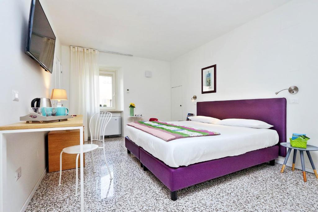 圣塞韦里诺马尔凯Guest House Viaroma的一间卧室配有一张紫色的床和一张书桌