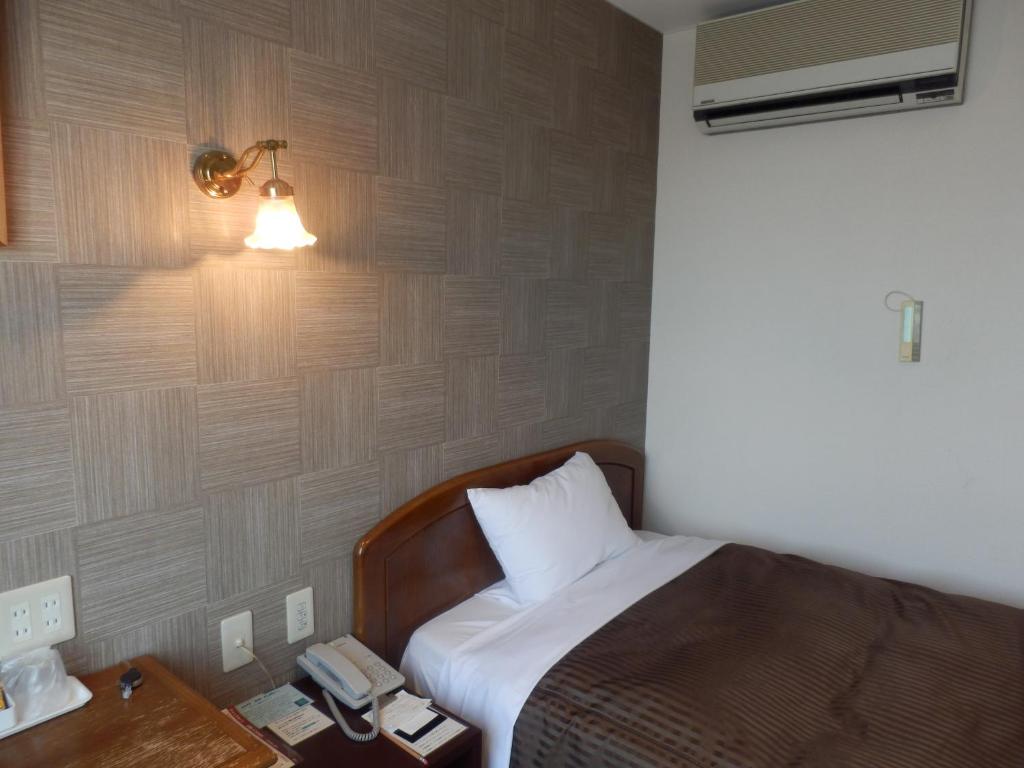 千叶幕张法米酒店的一间卧室配有一张带台灯的床和一部电话