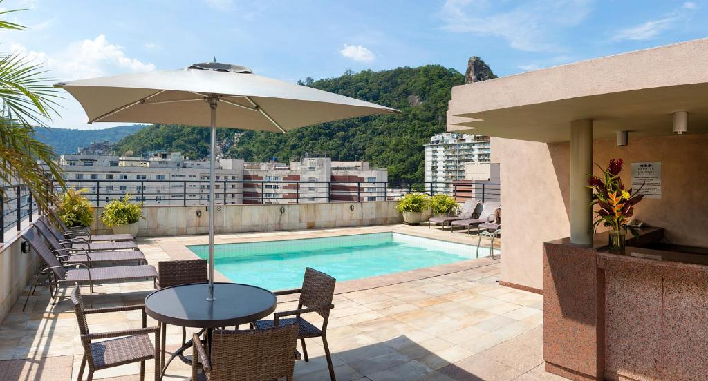 里约热内卢科帕卡巴纳顶级酒店的一个带桌子和遮阳伞的庭院和一个游泳池
