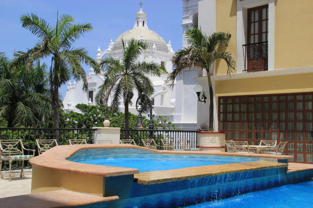 韦拉克鲁斯迪丽君西亚斯格伦酒店的棕榈树建筑前的游泳池