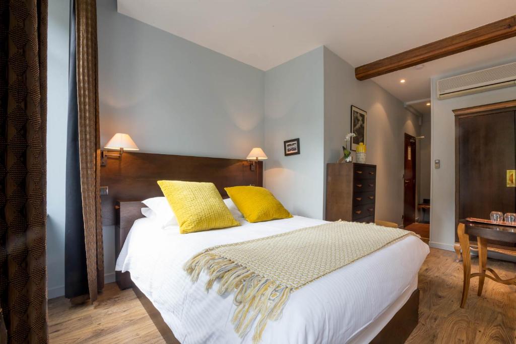 博讷Les Chambres de L'Ecrit'Vin - En plein coeur du centre-ville的一间卧室配有一张大床和两张黄色枕头