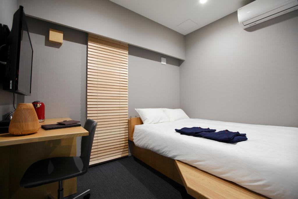 东京HOTEL AMANEK Ginza East的一间卧室配有一张床和一张带电脑的书桌