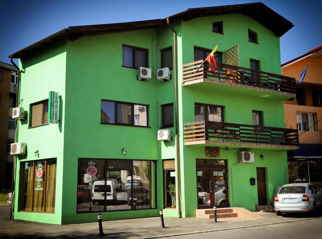 克拉约瓦Pensiunea Caramida Verde的绿色建筑,设有阳台和国旗