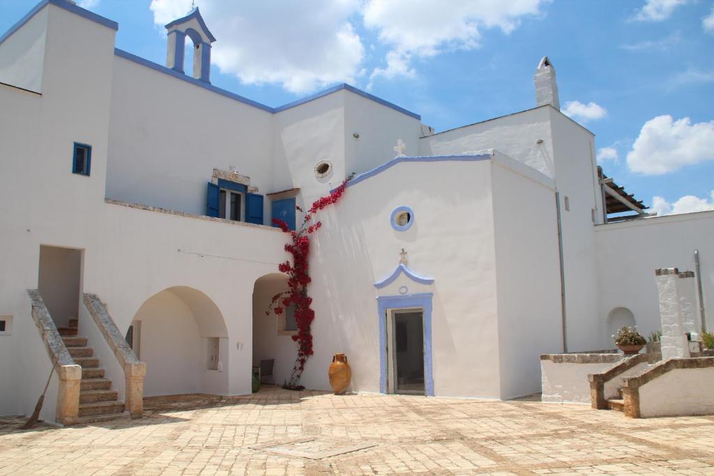 滨海波利尼亚诺Masseria San Martino的白色的教堂,有蓝色的门和楼梯