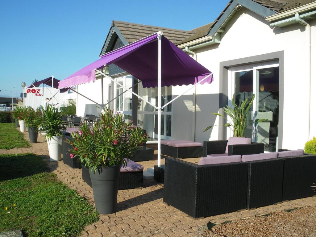 图尔The Originals City, Hôtel La Terrasse, Tours Nord (Inter-Hotel)的紫色的雨伞,椅子和植物在房子前面