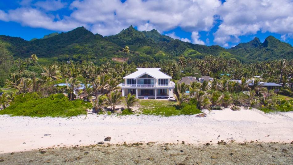 拉罗汤加Seaside Beachfront Villas Rarotonga的海滩上的房子,以群山为背景
