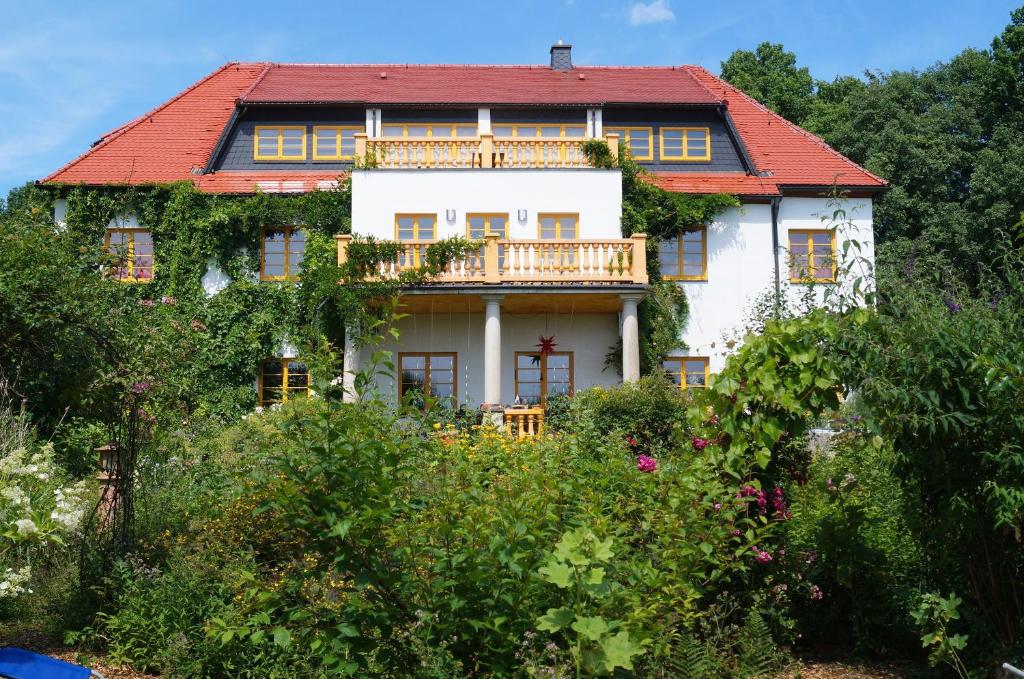 StruppenÖkopension Villa Weissig的一座大型白色房屋,设有红色屋顶