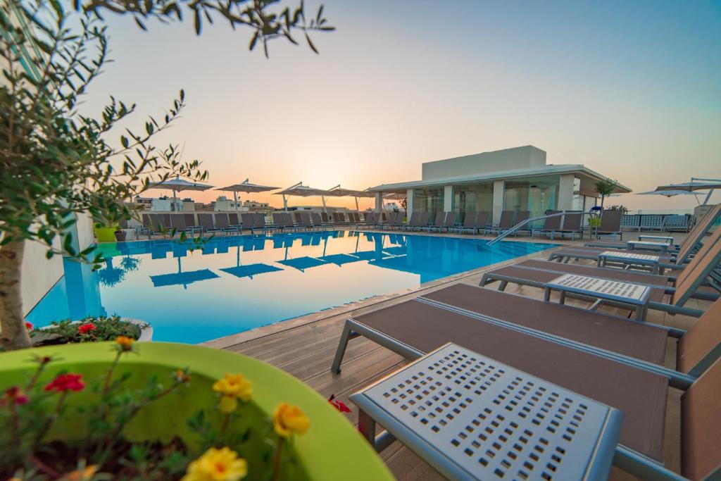 梅利哈玛丽蒂姆马耳他酒店的一座带桌椅的游泳池以及一座建筑