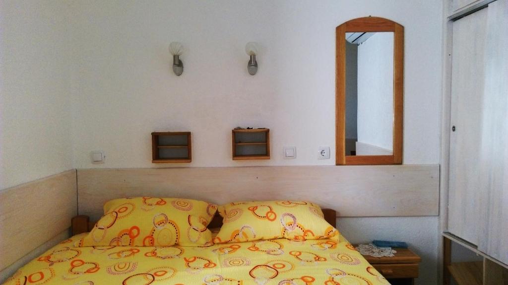乌尔齐尼Ema Apartments的一张带黄色被子和镜子的床