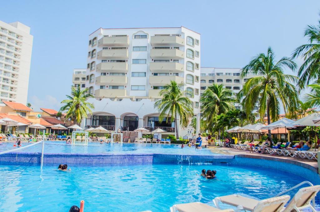 伊斯塔帕ENNA INN IXTAPA DEPARTAMENTO 01 RECAMARA ViSTA MAR的和水中的人在度假村的游泳池