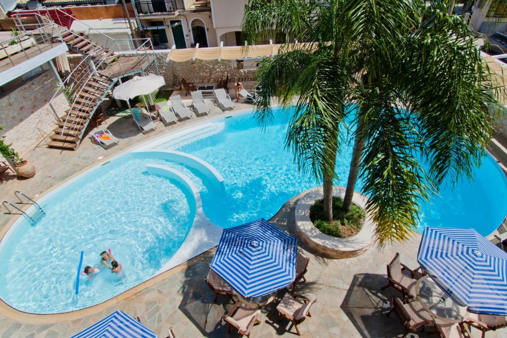 雷夫卡达镇艾昂尼昂之星酒店的享有带遮阳伞和棕榈树的游泳池的顶部景致