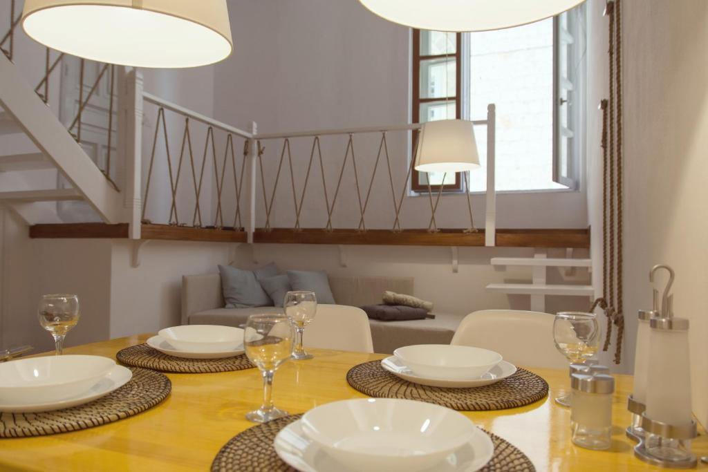 伊兹拉Alleyway House的用餐室配有带盘子和酒杯的桌子