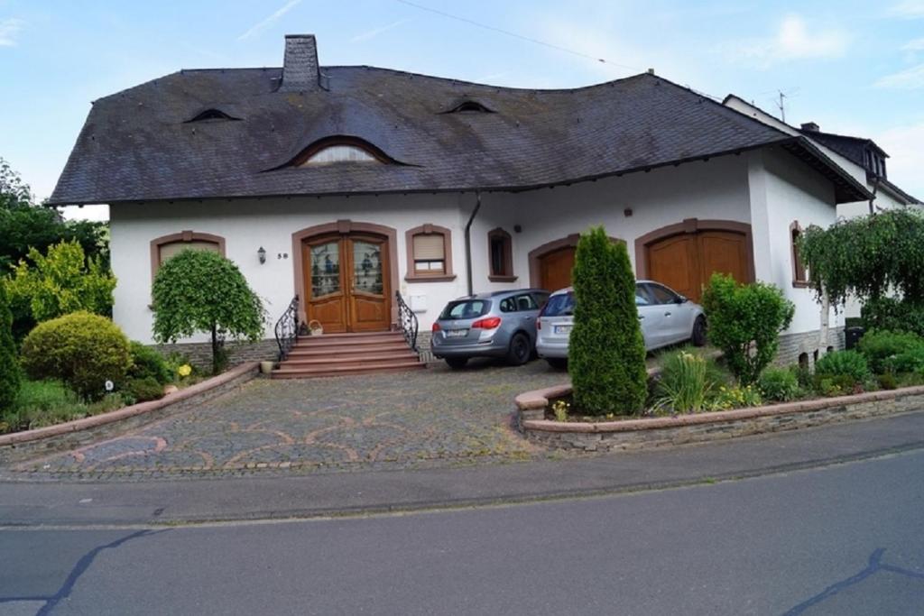 策尔廷根-拉蒂希Pension Birgit Pazen的一座白色的房子,前面有汽车停放