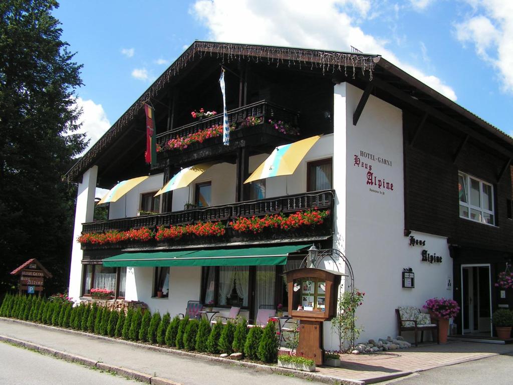 鲁波尔丁Hotel Garni Haus Alpine - Chiemgau Karte inkl的阳台上的黑色和白色建筑,鲜花盛开