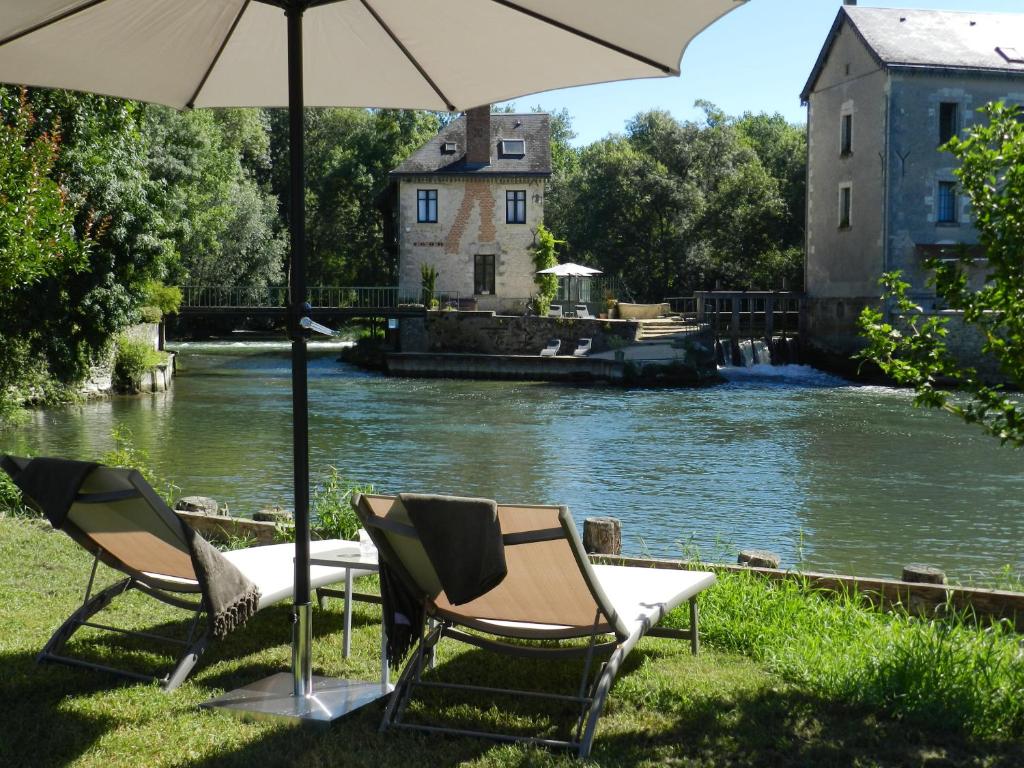 Saché雪弗里艾磨坊住宿加早餐旅馆的两把椅子和一把雨伞,旁边是一条河