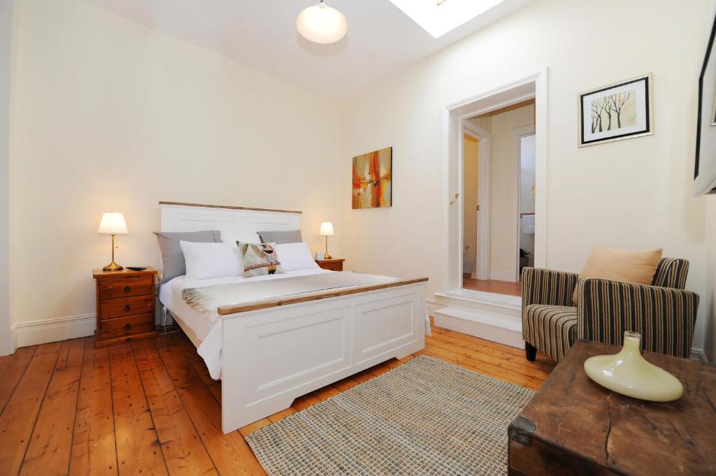 奥尔巴尼奥尔巴尼斯宾塞套房旅馆的卧室配有一张白色大床和一把椅子