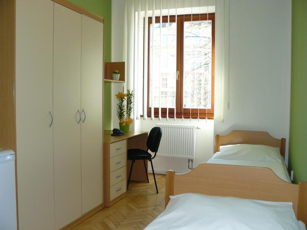 奥洛穆茨玛丽亚酒店旅馆的一间卧室设有两张床、一张桌子和一个窗口。