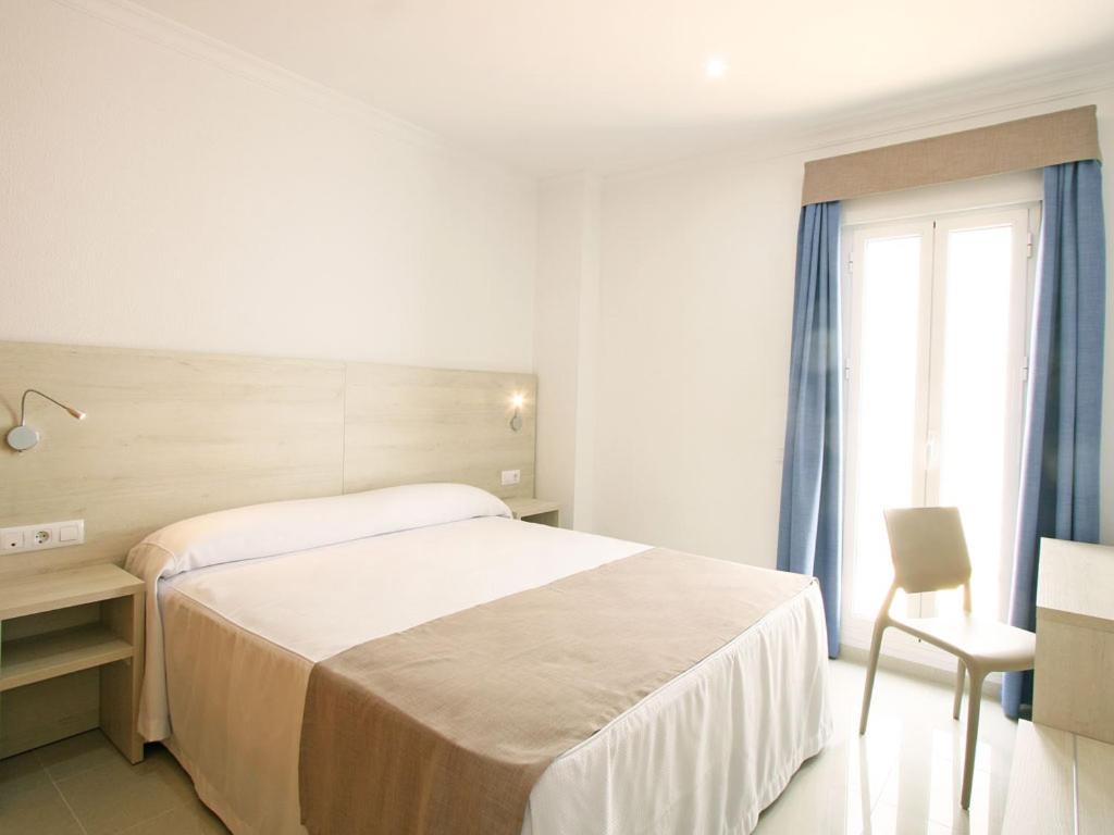 巴尔巴特AReH Apartamentos的一间卧室配有一张床、一张书桌和一个窗户。
