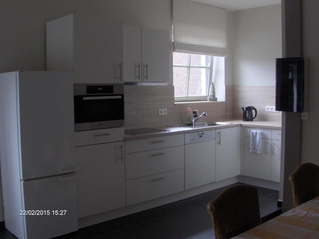 BoutersemWenceslas Cobergher Appartement II的厨房配有白色橱柜、水槽和冰箱。