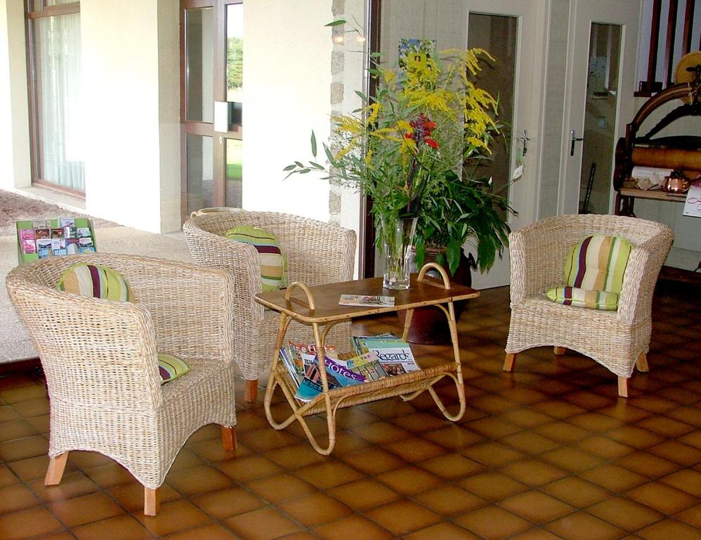La Ferté-MacéAuberge d'Andaines的客厅配有藤椅和桌子
