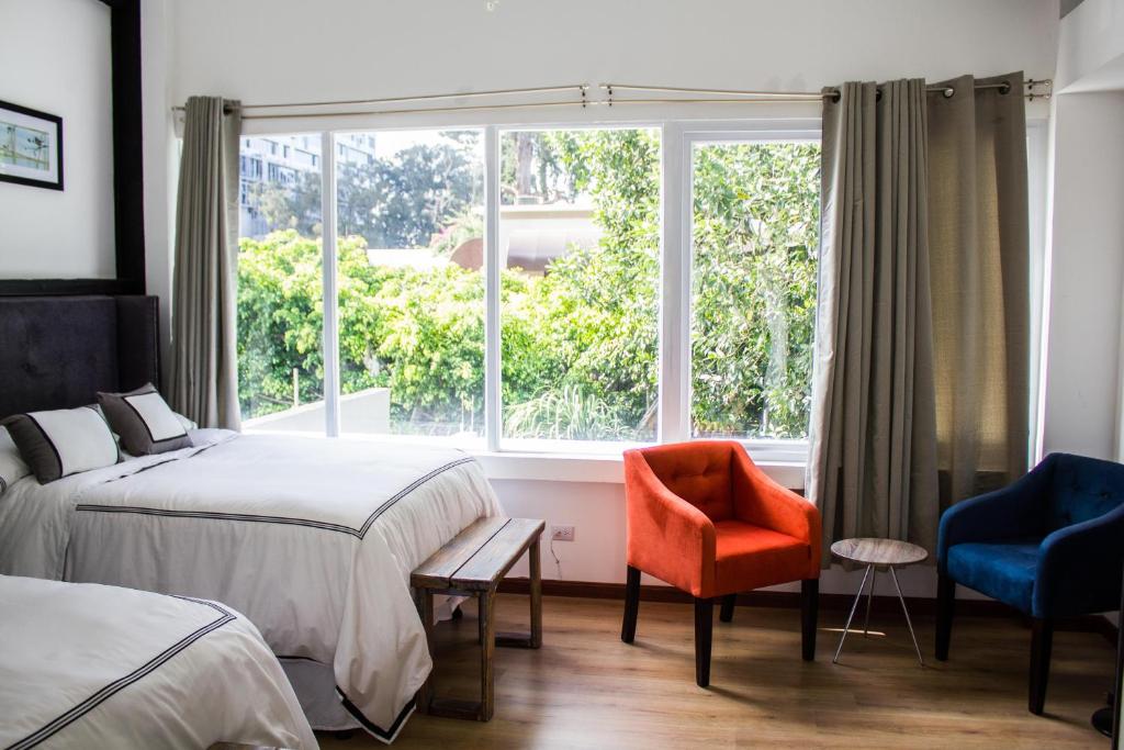 危地马拉梅拉奇精品酒店的一间卧室设有两张床、一个窗口和椅子