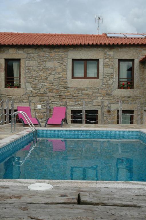 Duas IgrejasCasa de l Telar的游泳池旁的两把粉红色椅子
