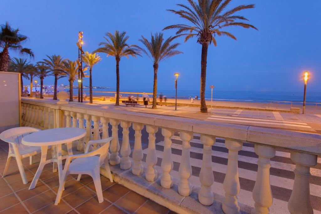 萨洛Apartamento Miramar的一个带桌椅和海滩的阳台