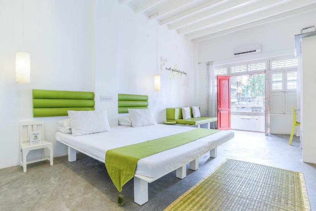 蓬蒂切里Itsy By Treebo - Red Lotus Heritage Promenade Beach的一间卧室配有一张绿色的大白色床。