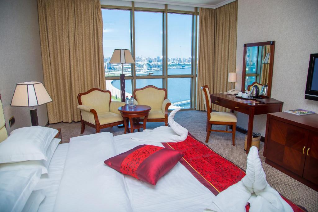 巴库Golden Coast Hotel的酒店客房设有一张大床、一张书桌和一张书桌。