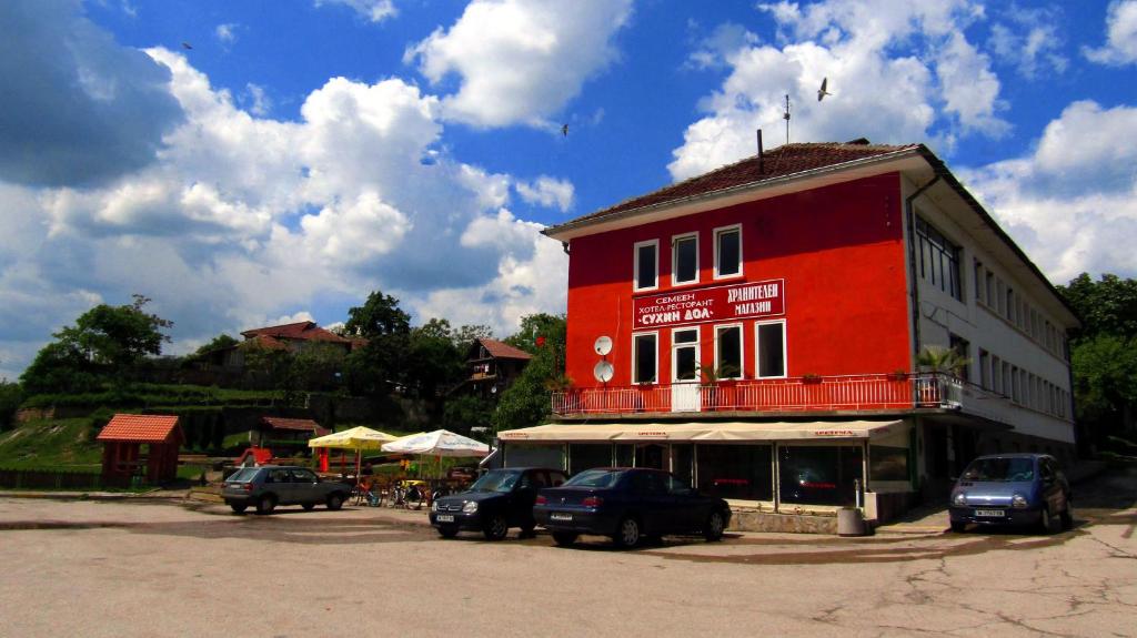 BelimelSuhin Dol Hotel的一座红色的建筑,前面有汽车停放