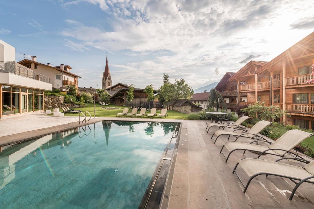 布列瑟农Apartment Lodge Gasserhof的一个带椅子的游泳池和教堂