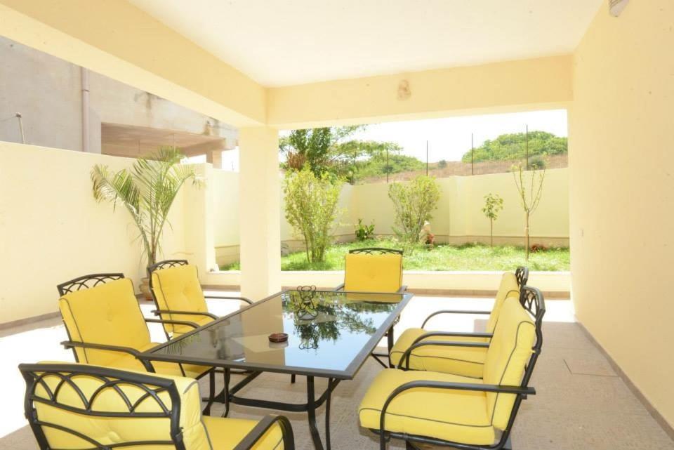 加利波利B&B IN VILLA的庭院设有玻璃桌和黄色椅子