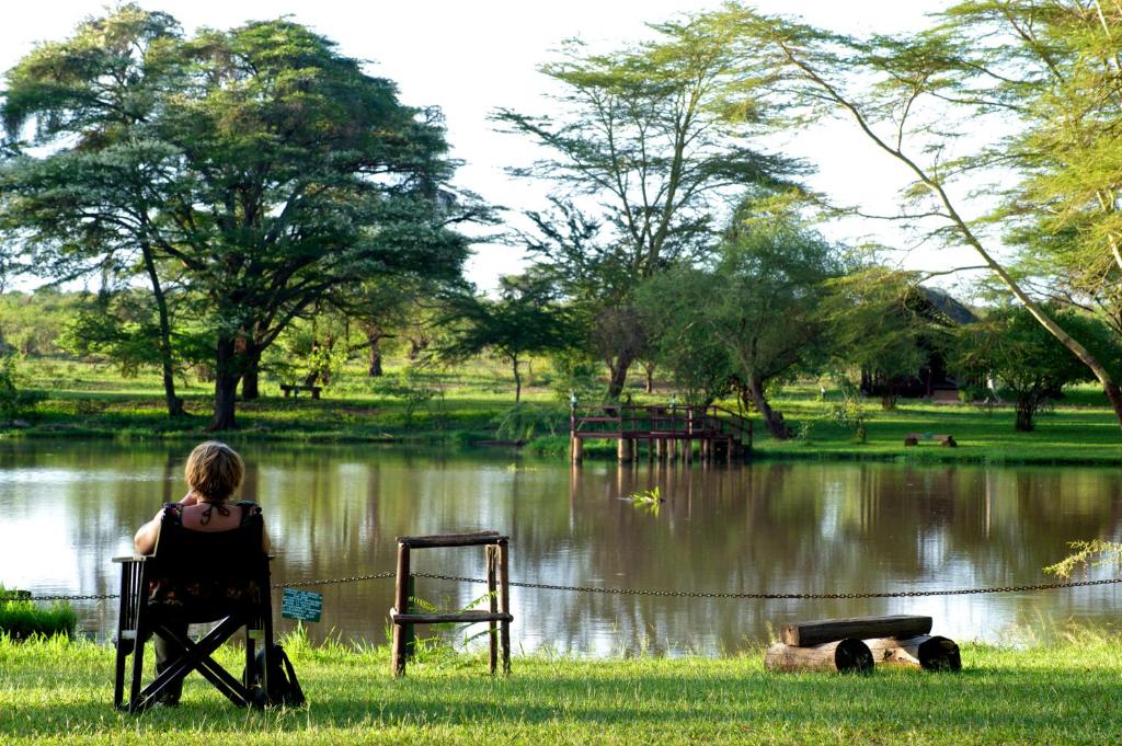 Ziwani瓦亚吉尔兹瓦尼帐篷营地酒店的坐在湖前椅子上的女人