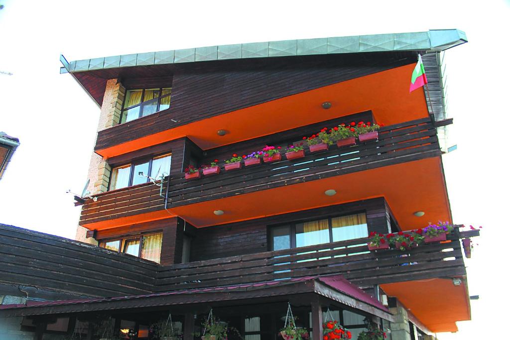 Chervena Lokva达斯卡洛夫旅馆的一座橙色的建筑,阳台上种植了盆栽植物
