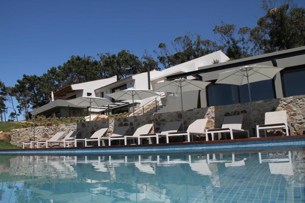 辛特拉昆塔瓦勒罗卡别墅 的一座带椅子和遮阳伞的游泳池位于一座建筑旁边