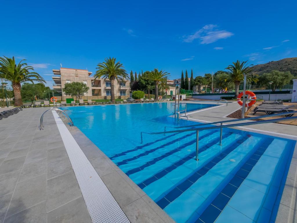 罗萨斯Agi Rescator Apartments的一座拥有蓝色海水和棕榈树的大型游泳池