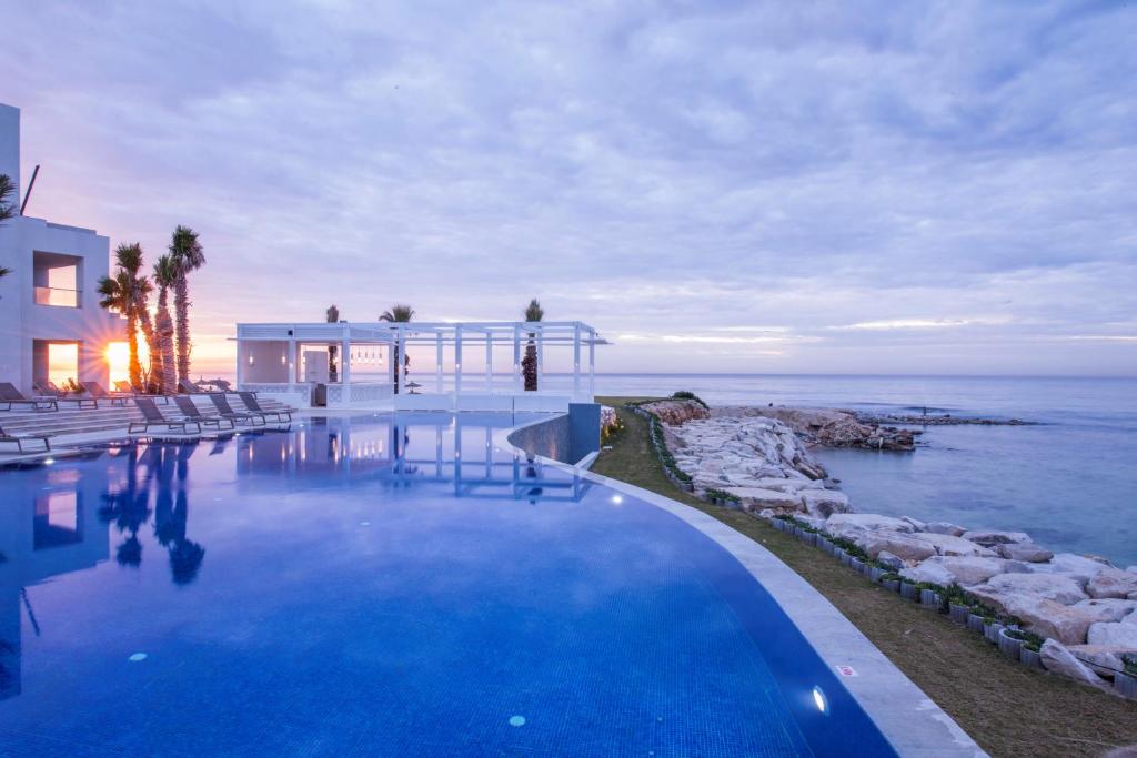 哈马马特巴迪拉成人酒店的一座位于房子和大海前的游泳池